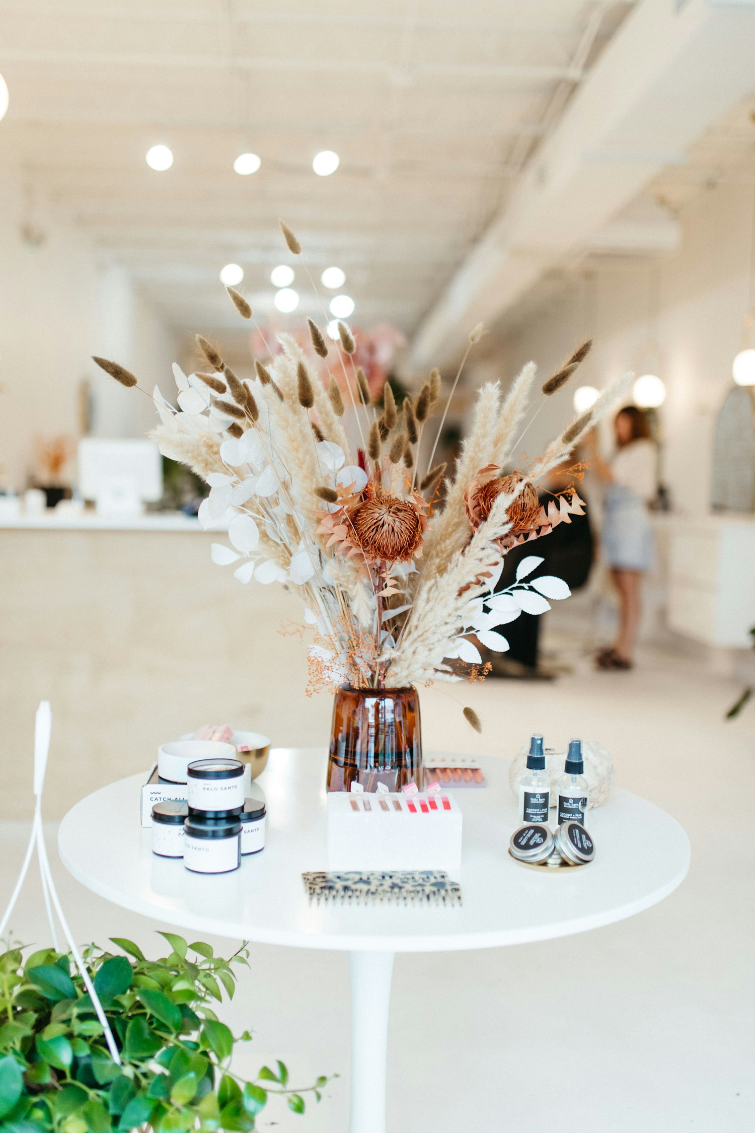 A bright salon styling area with a white table, dried florals and retail products